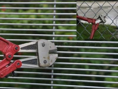A red bolt cutter nips chain link fence, but cannot even stretch into small holes of 358 fence.